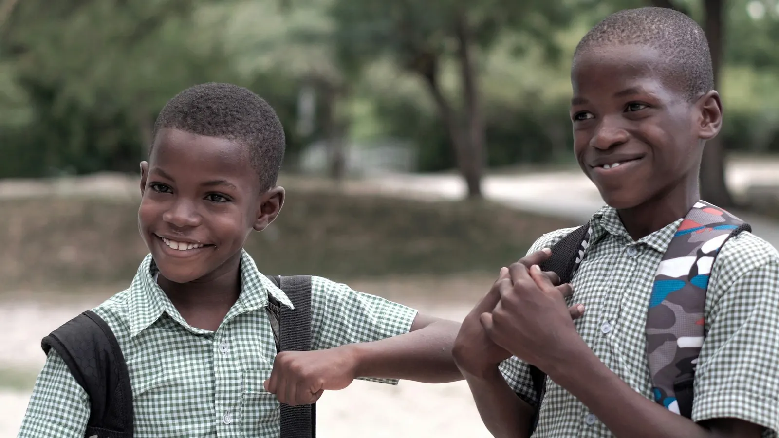 Two schoolboys laughing with their backpacks